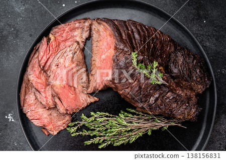 Sliced grilled beef hanger or onglet steak served on black plate with thyme and salt, dark stone background with copy space Sliced grilled beef hanger or onglet steak served on black plate with thyme and salt, dark stone background with copy space 138156831