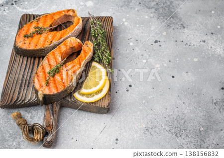 Cooked salmon steaks including sockeye with herbs citrus and seasoning on board, clean light background Cooked salmon steaks including sockeye with herbs citrus and seasoning on board, clean light background 138156832