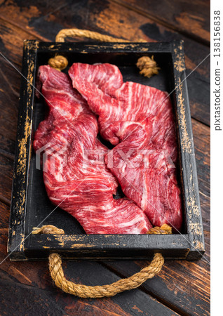 Closeup raw skirt beef steak with visible fibers and marbling on dark wooden background with rosemary and spices, uncooked protein ingredient for grilling 138156838