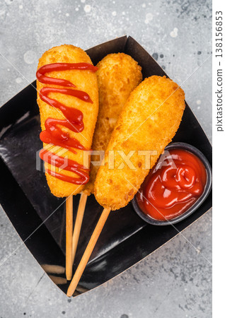Corn dogs in takeaway packaging with ketchup, crunchy fast food snack on light surface with copy space for advertising Corn dogs in takeaway packaging with ketchup, crunchy fast food snack on light surface with copy space for advertising 138156853