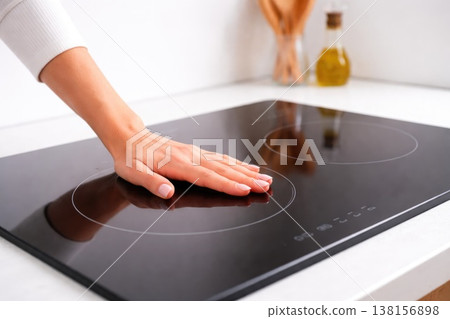 Hand touching modern induction stove kitchen technology safety concept Hand touching modern induction stove kitchen technology safety concept 138156898
