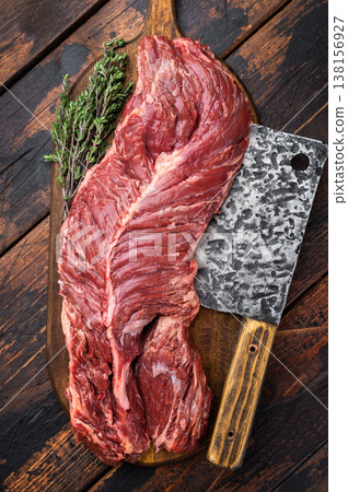 Fresh uncooked hanger steak diaphragm beef cut with knife on wooden board, pepper and thyme, dark rustic background ideal for cooking concept Fresh uncooked hanger steak diaphragm beef cut with knife on wooden board, pepper and thyme, dark rustic background ideal for cooking concept 138156927