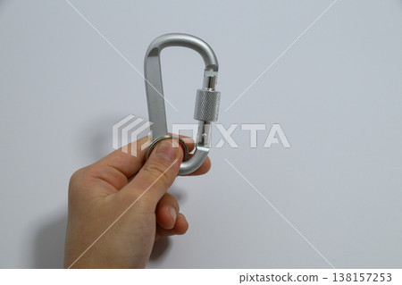 A metal carabiner and ring held in the hand. A metal carabiner and ring held in the hand. 138157253