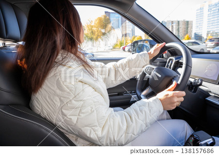 Confident woman with long brown hair driver in modern car, looking forward while holding the steering wheel. Safe driving behavior and road trip. designer, businesswoman Confident woman with long brown hair driver in modern car, looking forward while holding the steering wheel. Safe driving behavior and road trip. designer, businesswoman 138157686