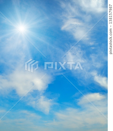 Beautiful vertical shot of a bright shining sun with long rays in a clear blue sky with soft white wispy clouds, representing a peaceful sunny day and high-altitude meteorological weather. Beautiful vertical shot of a bright shining sun with long rays in a clear blue sky with soft white wispy clouds, representing a peaceful sunny day and high-altitude meteorological weather. 138157987