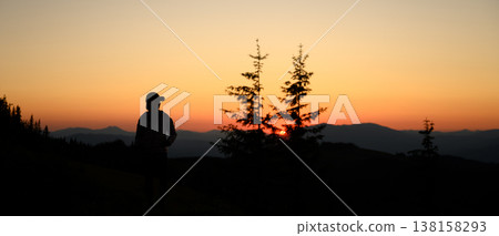 Silhouette of person standing on mountain ridge during sunset Silhouette of person standing on mountain ridge during sunset 138158293