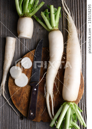 Sliced daikon radish with knife on rustic board Sliced daikon radish with knife on rustic board 138158295