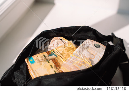 Close up of Kazakhstani tenge banknotes in black bag near window, savings and security concept Close up of Kazakhstani tenge banknotes in black bag near window, savings and security concept 138158438