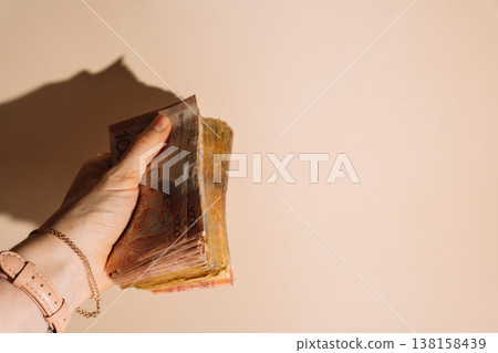 Close up hand holding Kazakhstani tenge banknotes on beige background with sunlight shadow, savings concept Close up hand holding Kazakhstani tenge banknotes on beige background with sunlight shadow, savings concept 138158439