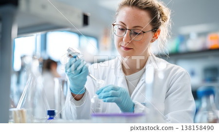 Female scientist performing laboratory experiment with pipette and glassware, showcasing research, healthcare, and scientific innovation 138158490