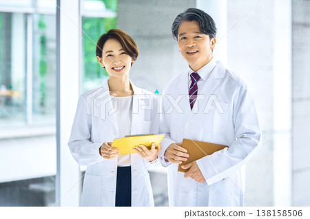 A portrait of a trustworthy Japanese doctor and medical staff member, both smiling and looking at the camera. A portrait of a trustworthy Japanese doctor and medical staff member, both smiling and looking at the camera. 138158506