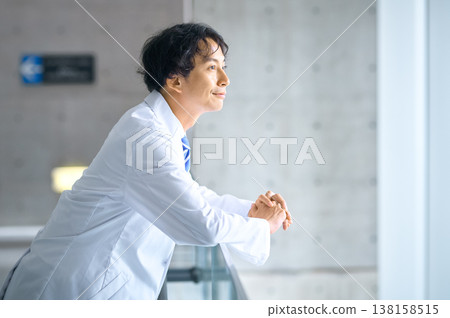 A trustworthy Japanese male doctor smiles, gazing into the future from a hospital window. A trustworthy Japanese male doctor smiles, gazing into the future from a hospital window. 138158515
