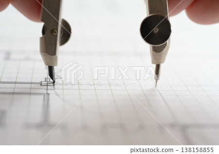 Close-up of an architect's hands working on a draft: creating architectural drawings using a compass. Close-up of an architect's hands working on a draft: creating architectural drawings using a compass. 138158855
