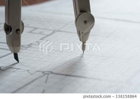 Close-up of an architect's hands working on a draft: creating architectural drawings using a compass. 138158864