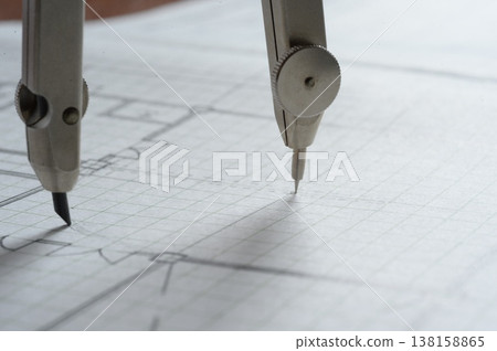 Close-up of an architect's hands working on a draft: creating architectural drawings using a compass. Close-up of an architect's hands working on a draft: creating architectural drawings using a compass. 138158865