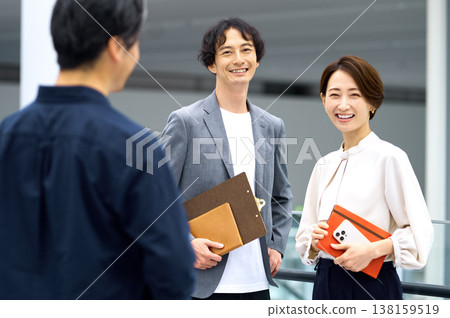 一群商務團隊成員面帶笑容地交談著。日本男女正在辦公室露台開會。 一群商務團隊成員面帶笑容地交談著。日本男女正在辦公室露台開會。 138159519