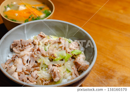 A homemade rice bowl with pork and soup served on a wooden table. A homemade rice bowl with pork and soup served on a wooden table. 138160370