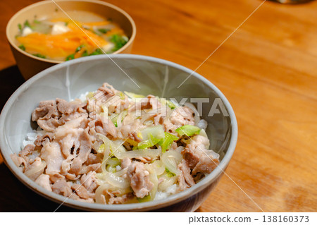 木桌上擺放著一碗豬肉飯和一碗湯；餐桌上留有文字空間。 138160373