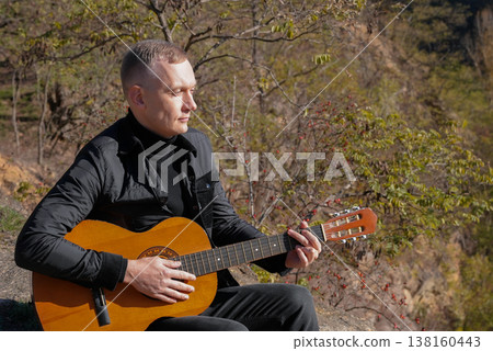 Blonde man playing string guitar outdoors in autumn forest. Concept of sound therapy, mental health and wellness rituals. Calmness tranquility audio-sensory practices. Aura farming energy Blonde man playing string guitar outdoors in autumn forest. Concept of sound therapy, mental health and wellness rituals. Calmness tranquility audio-sensory practices. Aura farming energy 138160443