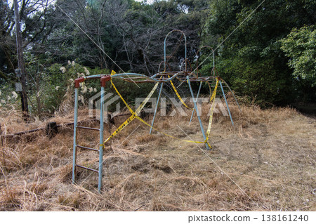 The abandoned monkey bars and withered weeds create a somewhat melancholic scene of playground equipment. The abandoned monkey bars and withered weeds create a somewhat melancholic scene of playground equipment. 138161240