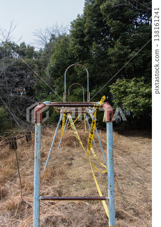 The abandoned monkey bars and withered weeds create a somewhat melancholic scene of playground equipment. 138161241