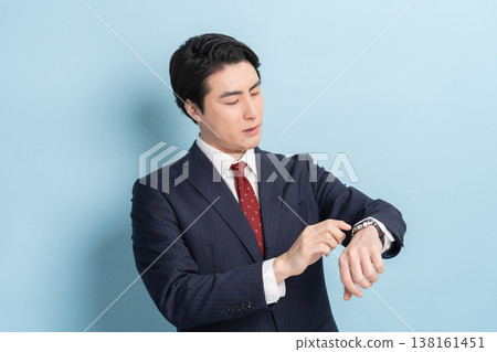 一位商人正在看手錶(藍色背景) 一位商人正在看手錶(藍色背景) 138161451