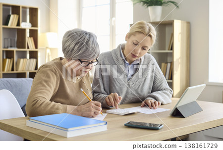 Adult daughter helping senior mother pay household bills and manage finances Adult daughter helping senior mother pay household bills and manage finances 138161729