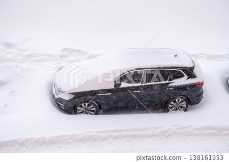 Snow-covered car during heavy winter snowfall on city street Snow-covered car during heavy winter snowfall on city street 138161953