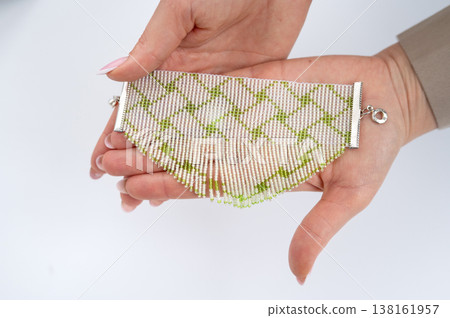 Handcrafted green and white beaded necklace in caucasian female hands Handcrafted green and white beaded necklace in caucasian female hands 138161957