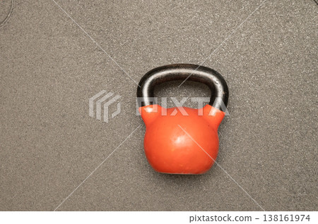 Red kettlebell on gray surface for strength training and fitness workouts Red kettlebell on gray surface for strength training and fitness workouts 138161974