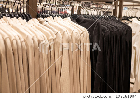 Neutral and black long-sleeve shirts on hangers in clothing store 138161994