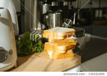 Stack of white bread slices with lettuce on kitchen counter in sunlight Stack of white bread slices with lettuce on kitchen counter in sunlight 138162000