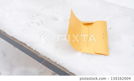 Yellow envelope on snow-covered bench in winter outdoor setting Yellow envelope on snow-covered bench in winter outdoor setting 138162004