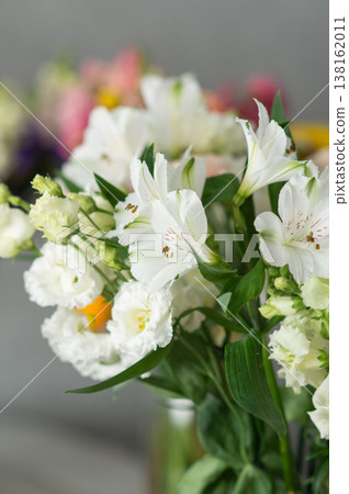 Vibrant bouquet of white alstroemeria and lisianthus flowers with green leaves in floral arrangement Vibrant bouquet of white alstroemeria and lisianthus flowers with green leaves in floral arrangement 138162011
