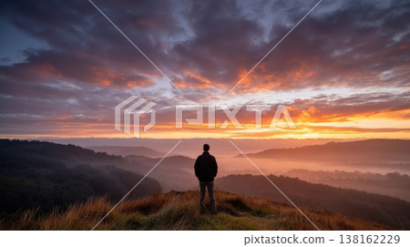 Lone person watching dramatic sunrise over misty hills for motivational background and landscape banner design Lone person watching dramatic sunrise over misty hills for motivational background and landscape banner design 138162229