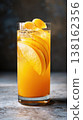 Tall highball glass filled with orange juice and ice on table 138162356