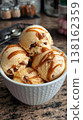 Caramel ripple ice cream scoops drizzled in white bowl 138162359