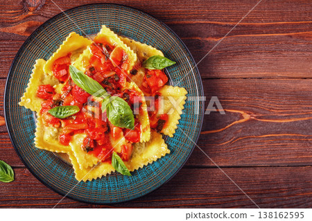 Ravioli with tomato sauce and basil on dark background. Ravioli with tomato sauce and basil on dark background. 138162595