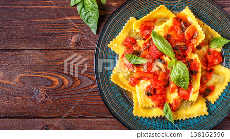 Ravioli with tomato sauce and basil on dark background. Ravioli with tomato sauce and basil on dark background. 138162596