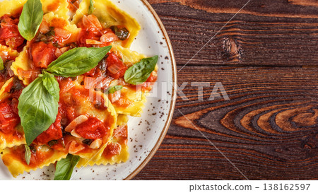 Ravioli with tomato sauce and basil on dark background. Ravioli with tomato sauce and basil on dark background. 138162597