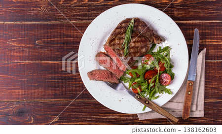 Ribeye steak with arugula and tomatoes. Ribeye steak with arugula and tomatoes. 138162603