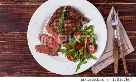 Ribeye steak with arugula and tomatoes. Ribeye steak with arugula and tomatoes. 138162604