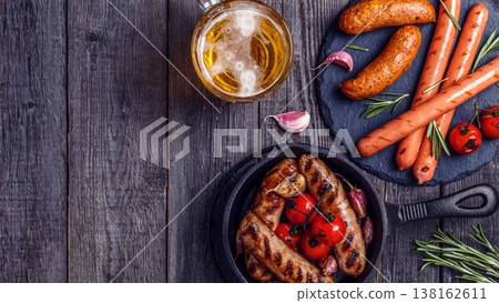 Grilled sausages with glass of beer on wooden table. Grilled sausages with glass of beer on wooden table. 138162611