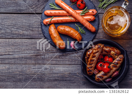 Grilled sausages with glass of beer on wooden table. Grilled sausages with glass of beer on wooden table. 138162612