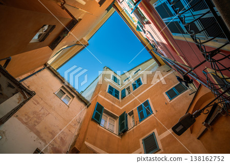 Buildings in laigueglia, liguria, italy, display traditional architecture with colorful facades and windows, framing an opening to the clear blue sky above 138162752