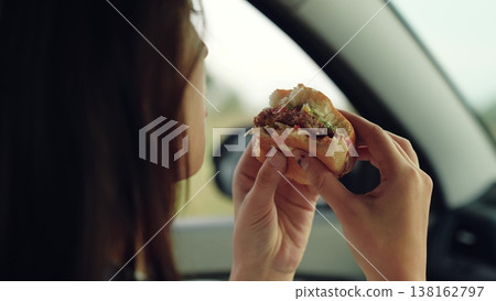 woman girl eating burger car, happy person, Girl enjoys fast food, Eating on the move, Sitting in car, Nature views outside, Quick tasty lunch, Burger with lettuce, Calm and relaxed, Hands gripping woman girl eating burger car, happy person, Girl enjoys fast food, Eating on the move, Sitting in car, Nature views outside, Quick tasty lunch, Burger with lettuce, Calm and relaxed, Hands gripping 138162797