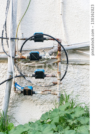 Old water supply pipes with valves and meters mounted on exterior wall of residential building. Urban infrastructure and water distribution system concept 138162823
