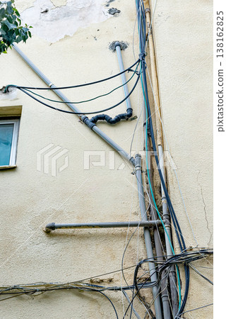 Old water supply pipes with valves and meters mounted on exterior wall of residential building. Urban infrastructure and water distribution system concept 138162825