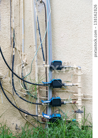 Old water supply pipes with valves and meters mounted on exterior wall of residential building. Urban infrastructure and water distribution system concept 138162826