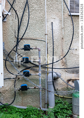 Old water supply pipes with valves and meters mounted on exterior wall of residential building. Urban infrastructure and water distribution system concept 138162828